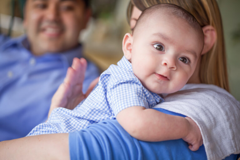 Happy Attractive Mixed Race Couple Burping Their Son.